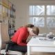 woman in red long sleeves with head leaning on laptop