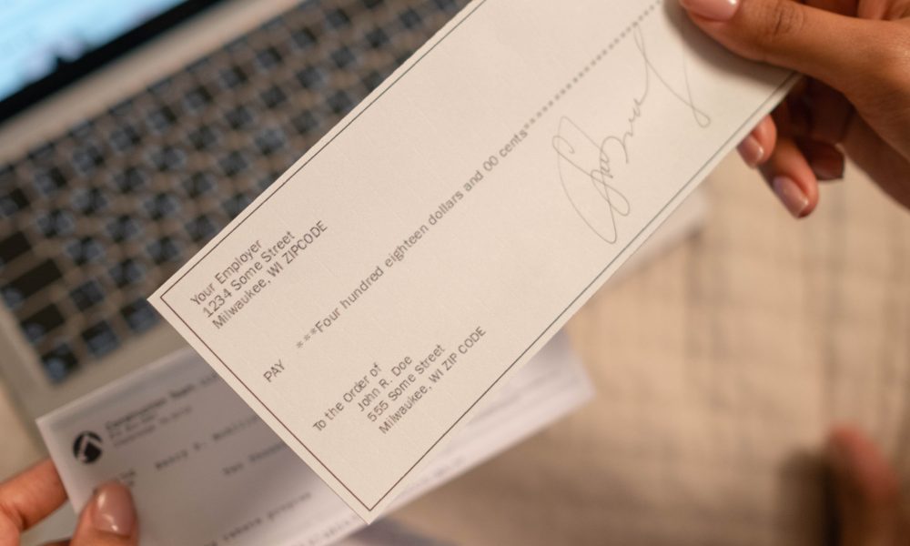 A Person's Hand Holding a Cheque
