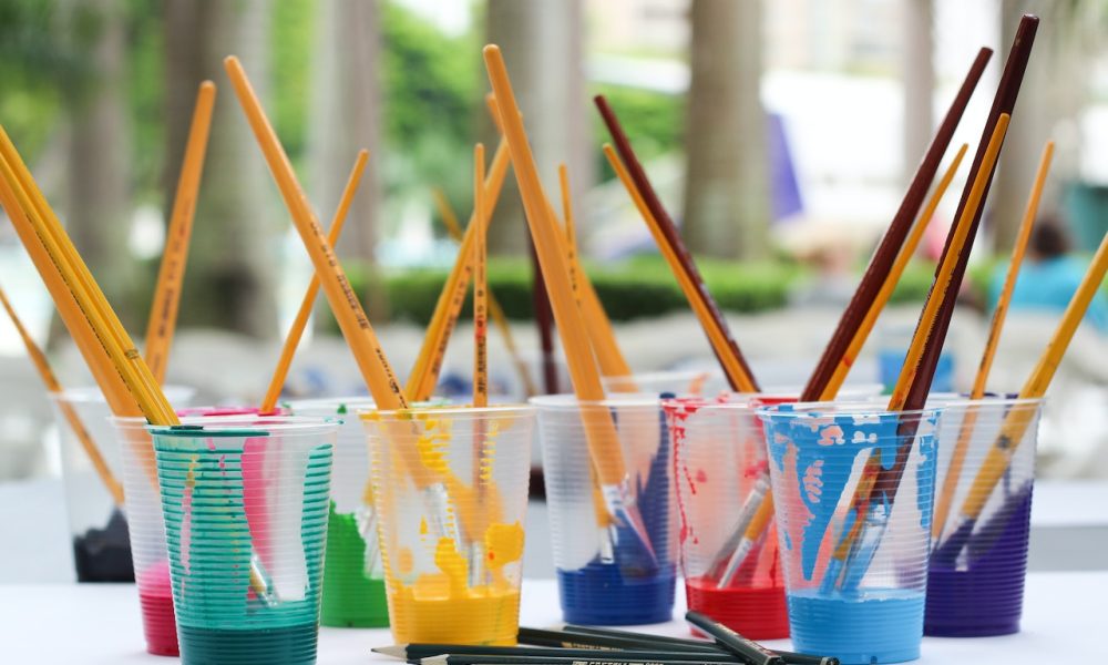 paint brushes and paints on clear cups