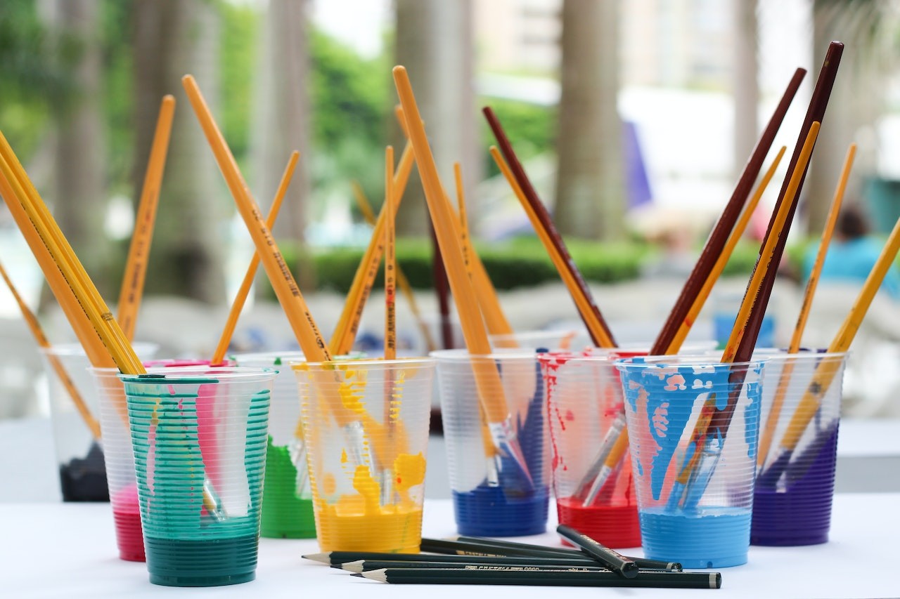 paint brushes and paints on clear cups