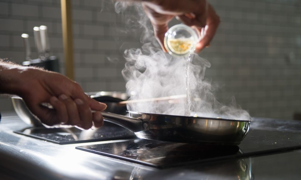 person putting on on frying pan on top of electric stove