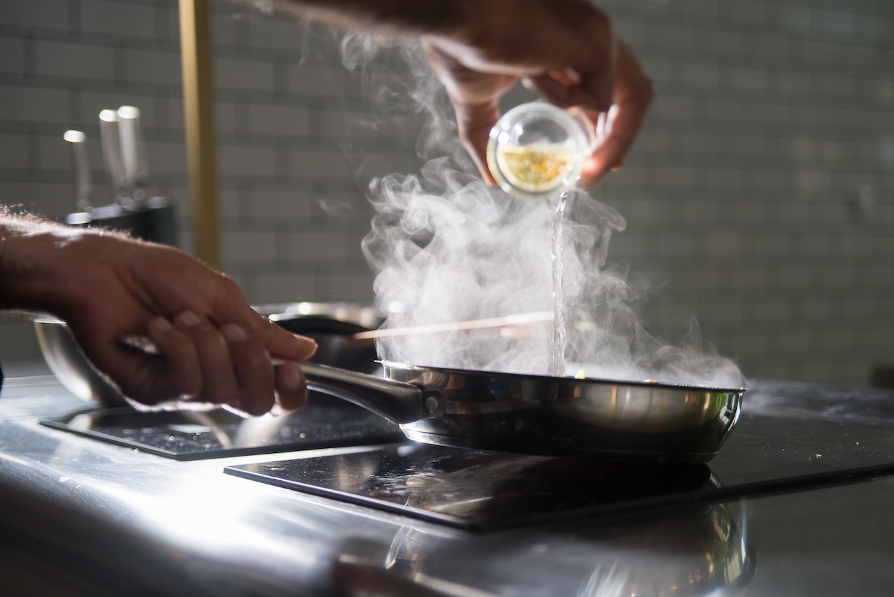 person putting on on frying pan on top of electric stove