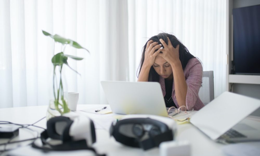 woman holding her head in front of laptop