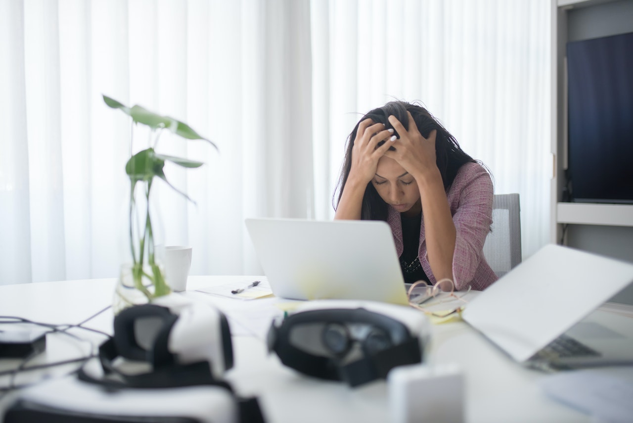 woman holding her head in front of laptop