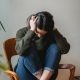 Anxious young woman cover wing ears with hands sitting on chair