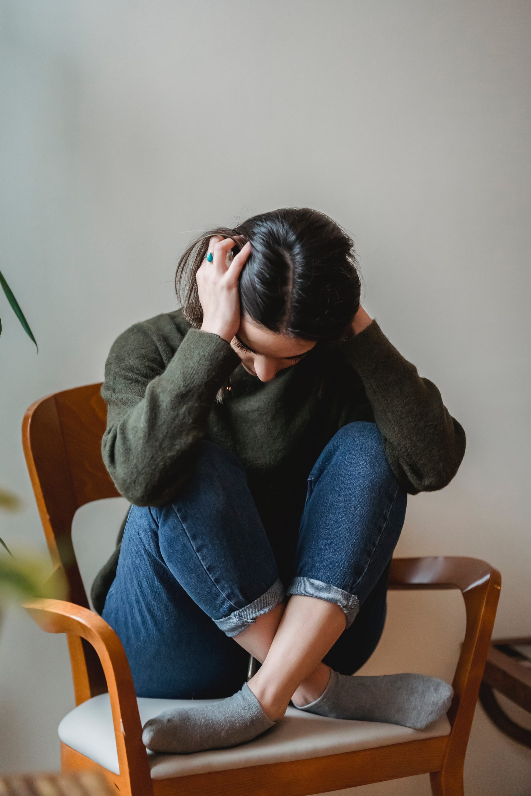 Anxious young woman cover wing ears with hands sitting on chair