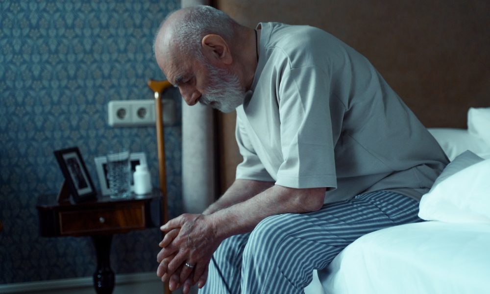 elderly man sitting on bed