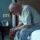 elderly man sitting on bed