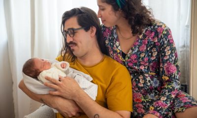 A Woman in Floral Dress Looking at Her Baby Carrying by the Father