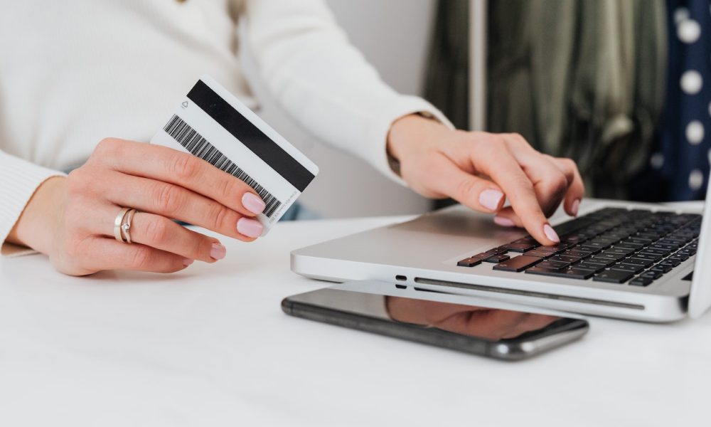 woman holding card and laptop in front