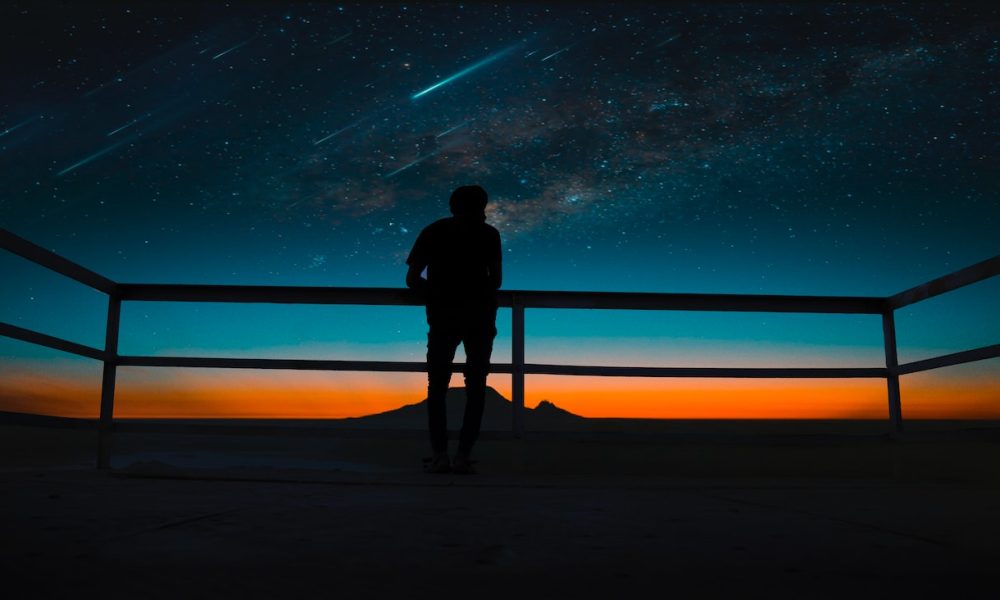 silhouette of man and meteor shower