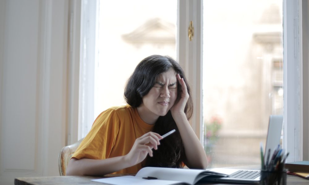 Female student suffering from headache at home