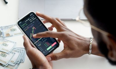hands holding phone with trade graphs