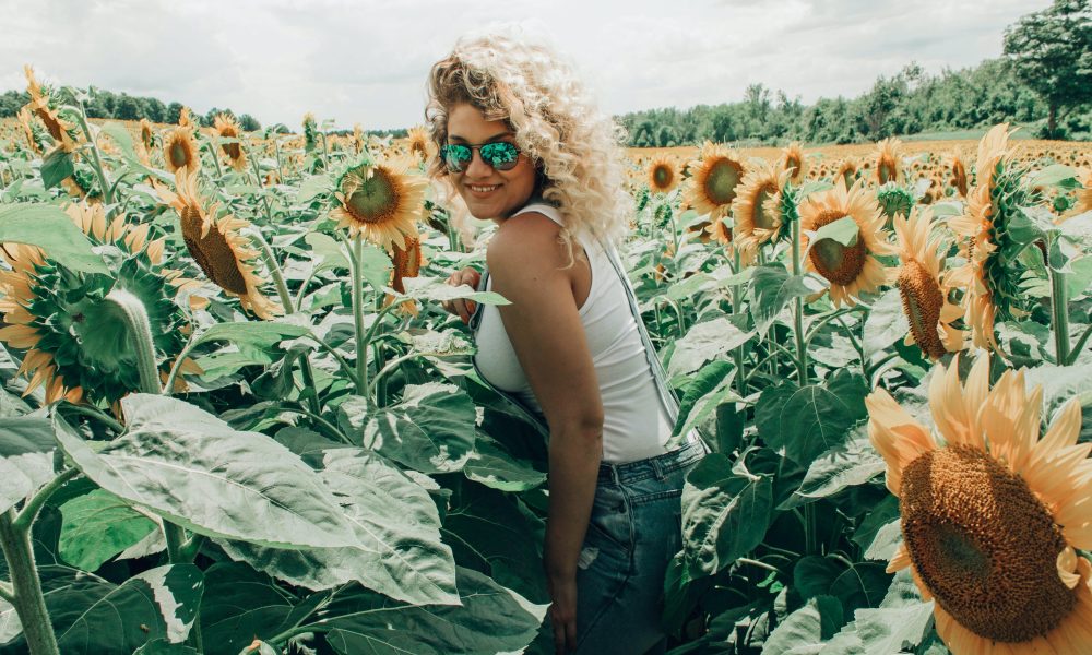 Woman in White Tank Top Standing in Sunflower Field