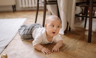 A Baby Crawling On Wooden Floor