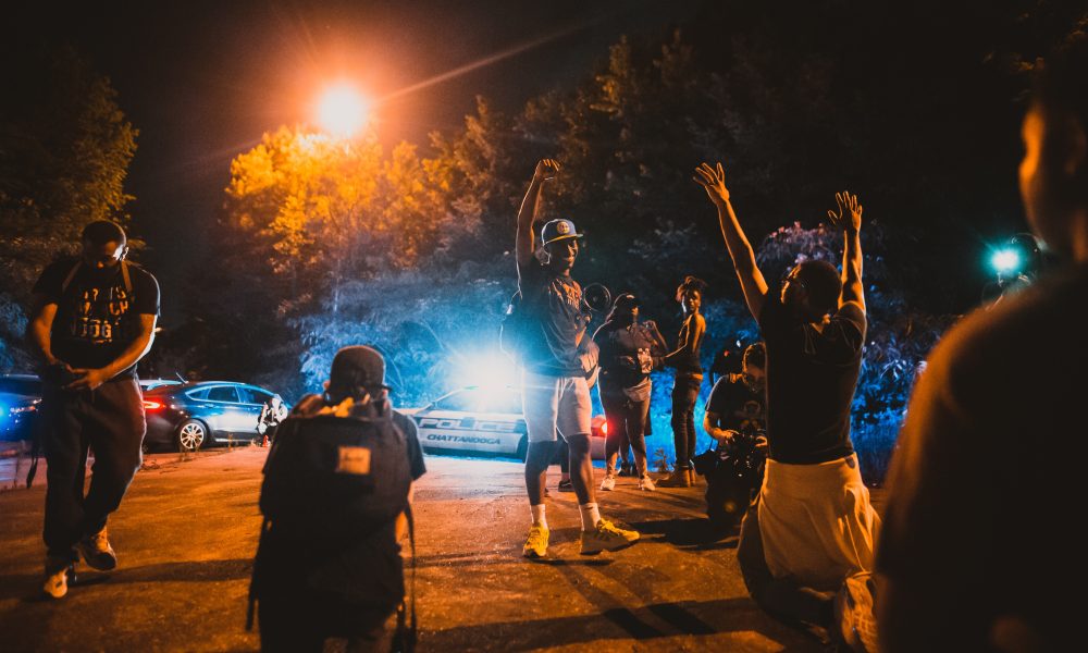 Black men standing on street near journalists and police car during anti racism demonstration