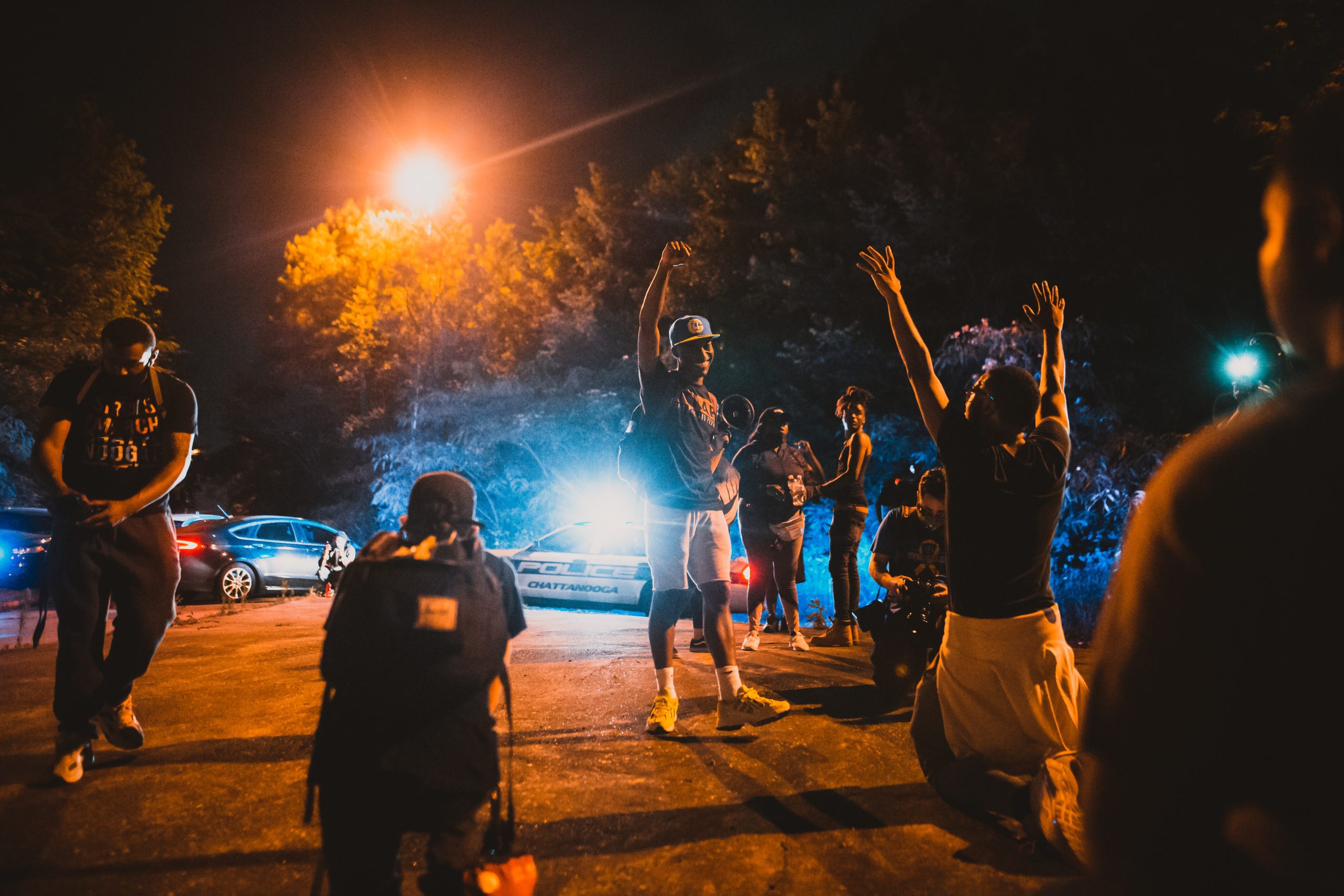 Black men standing on street near journalists and police car during anti racism demonstration