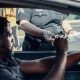 A Man Sitting Inside the Car Handing the License to the Police Officer