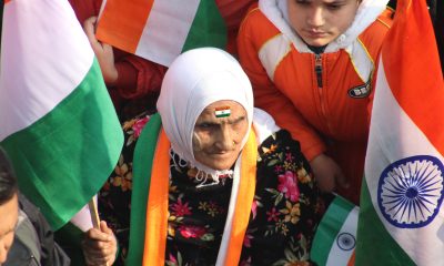 An Elderly Woman Sitting With A Group of People While Holding A Flag