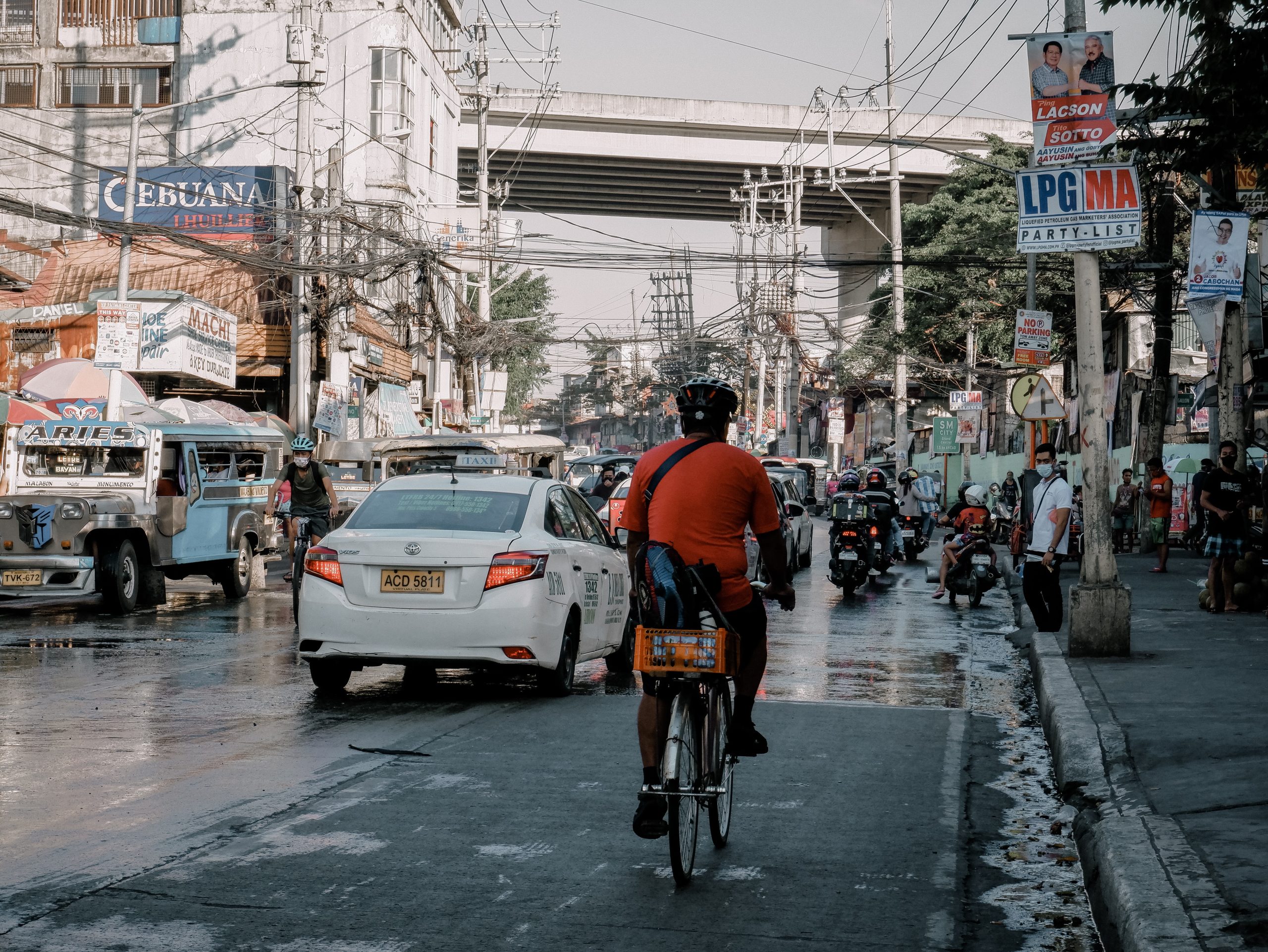 Man in Orange Shirt Riding a Bicycle on the Road Manila