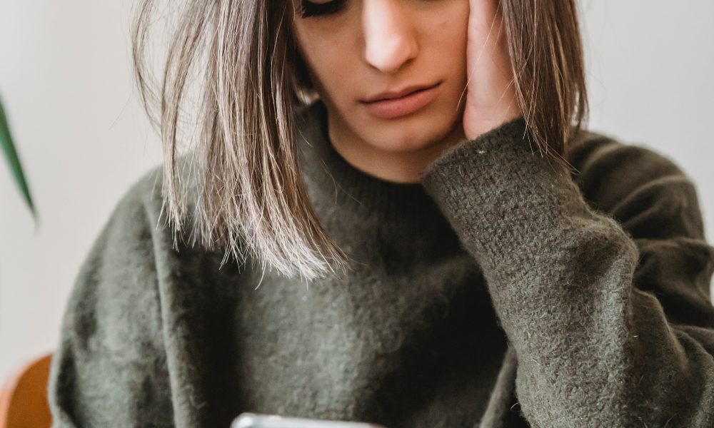 Concerned woman browsing smartphone in room