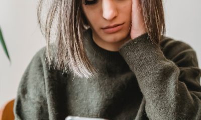 Concerned woman browsing smartphone in room