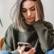 Concerned woman browsing smartphone in room