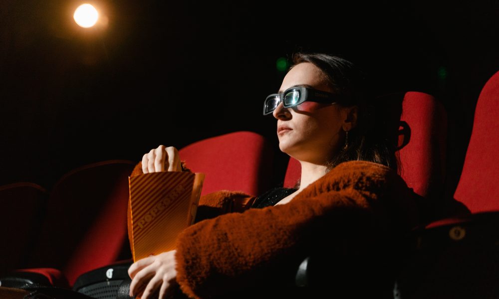 A Woman Wearing 3D Glasses while Watching a Movie in a Cinema