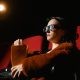 A Woman Wearing 3D Glasses while Watching a Movie in a Cinema