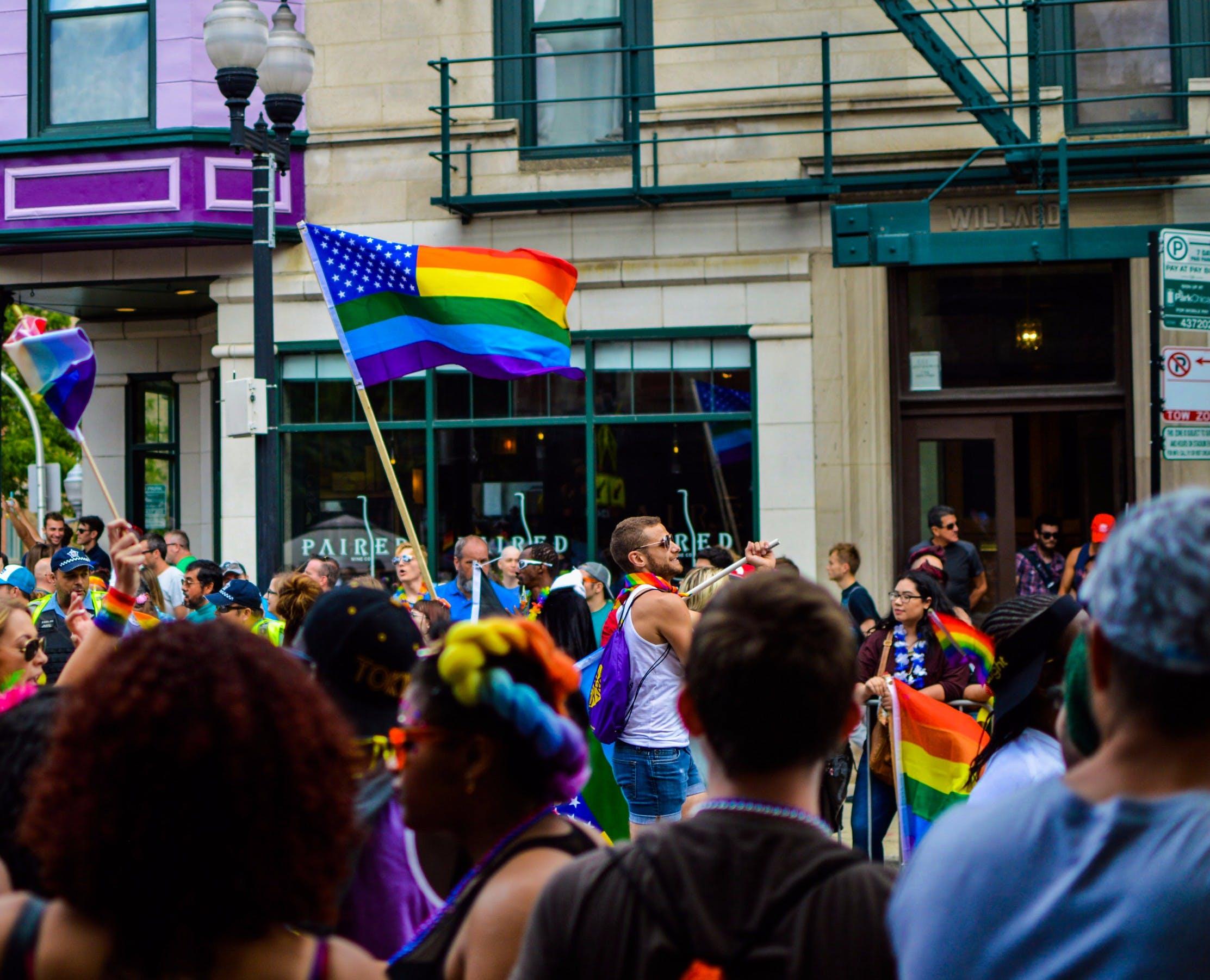 People Gathered Near Building Holding LGBT Flag at Daytime