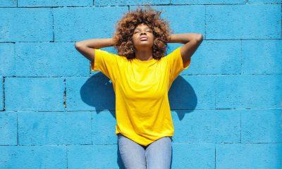 A Lady in Yellow Shirt Leaning Against Blue Brick Wall