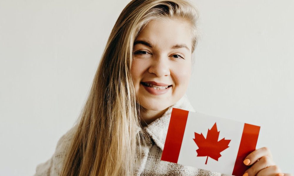 Woman Smiling while Holding a Canadian Flag