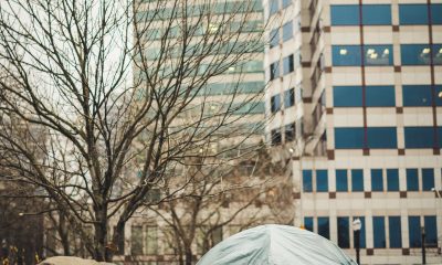 Shabby tents placed near modern buildings
