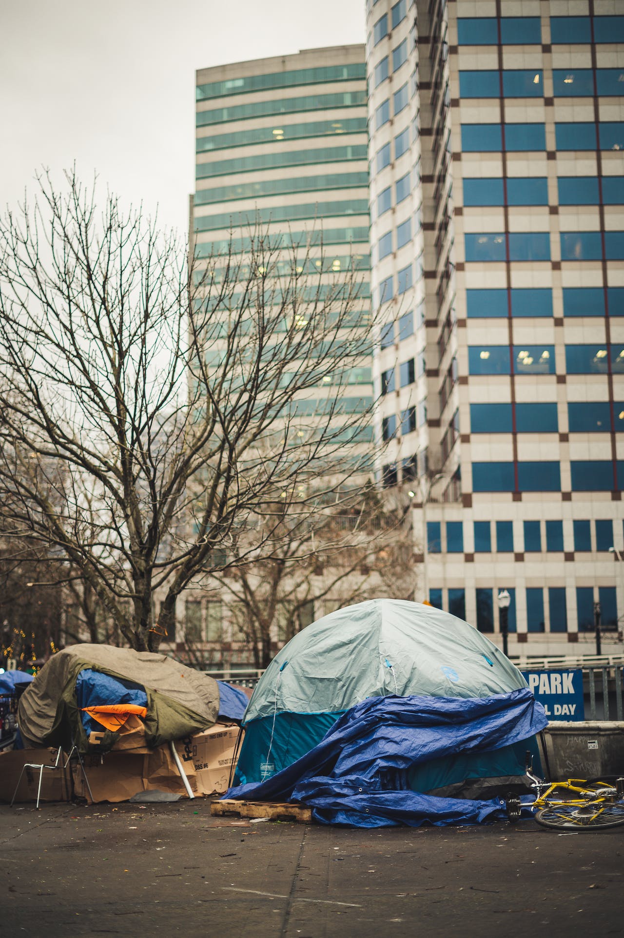 Shabby tents placed near modern buildings