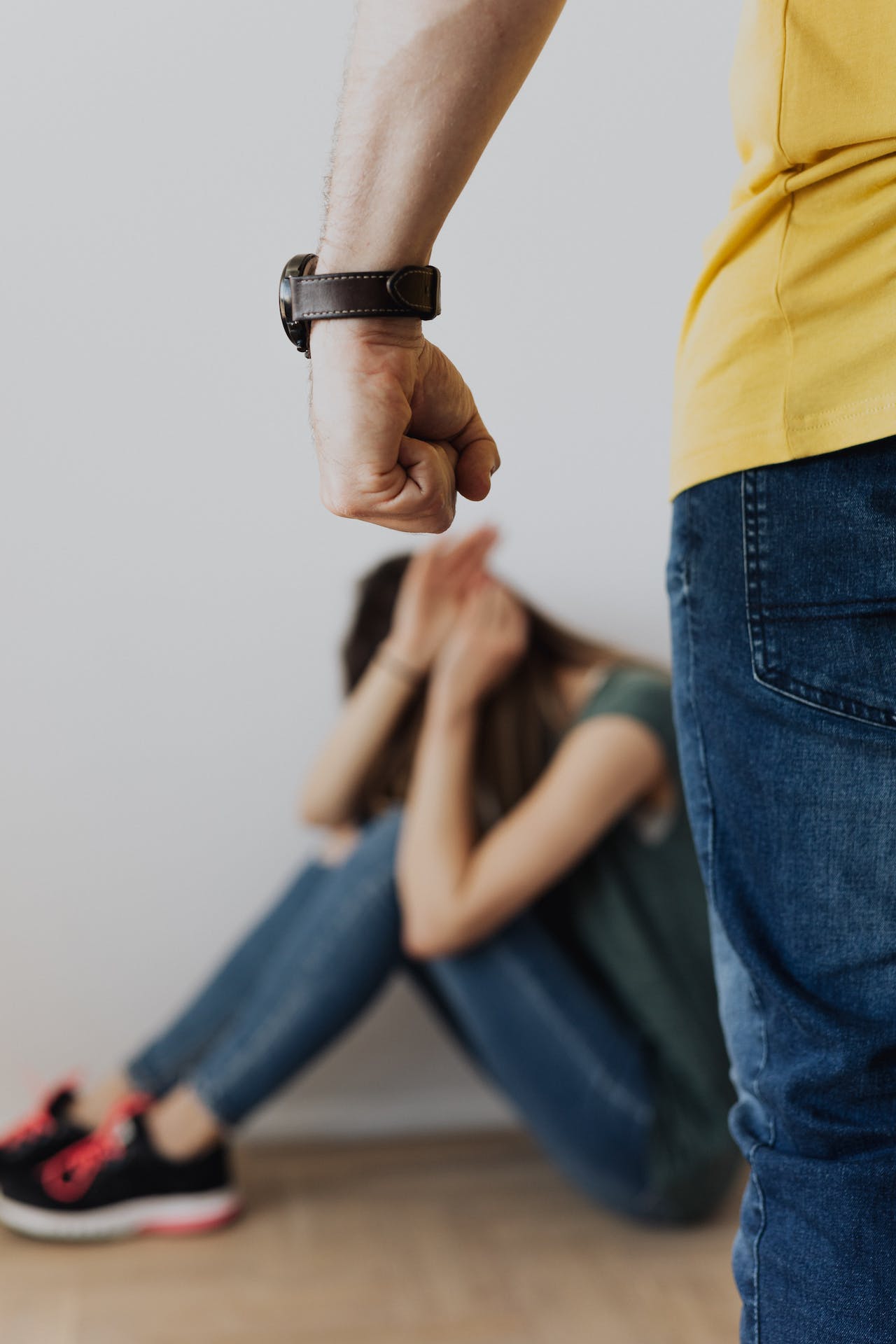Man in Yellow Shirt and Blue Denim Jeans Clenching Fist Near a Woman in Green Top