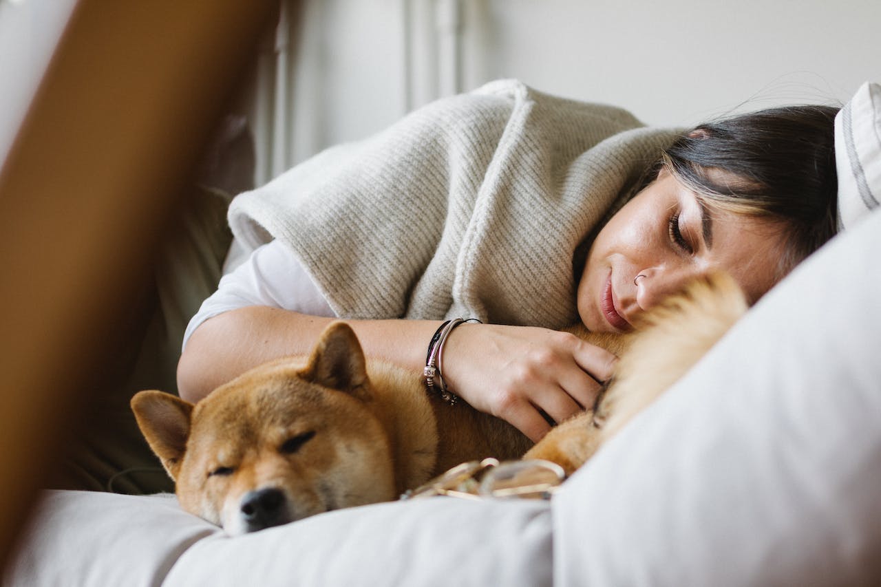 woman sleeping with dog on bed