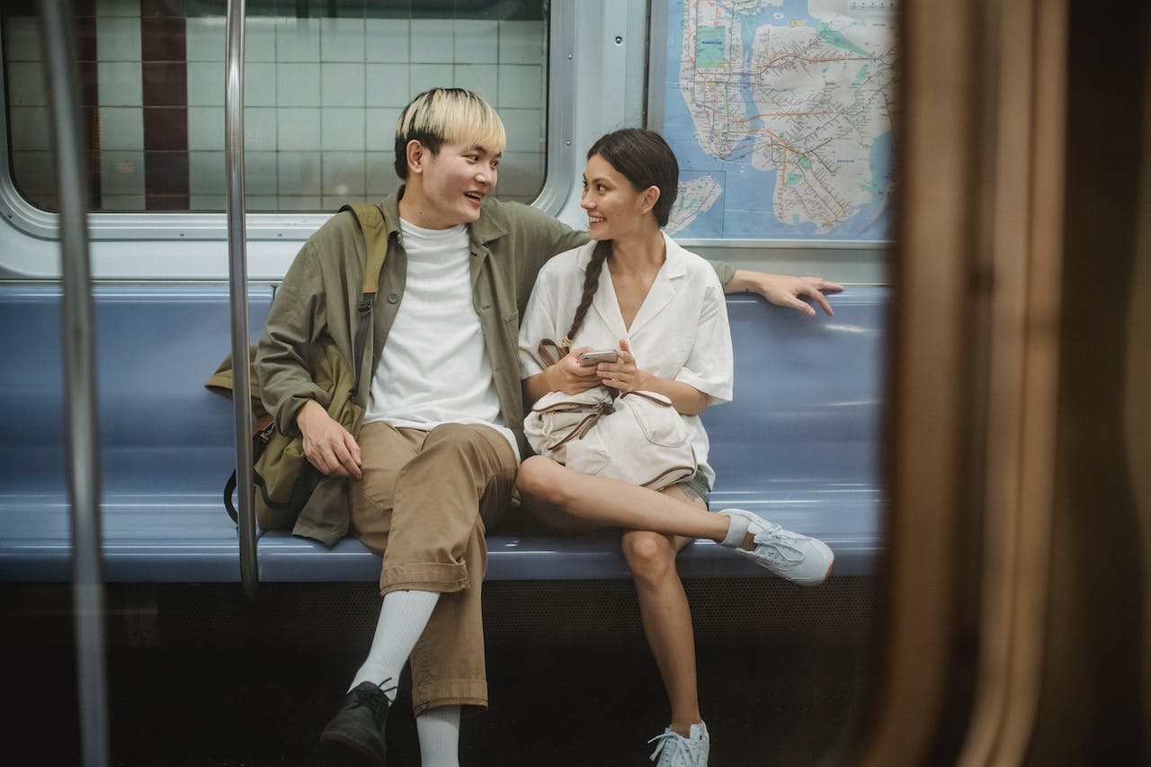 appy young ethnic couple sitting in train and talking