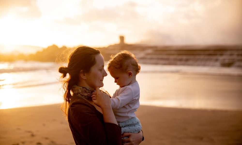 Shallow Focus Photo of Mother Carrying Her Baby