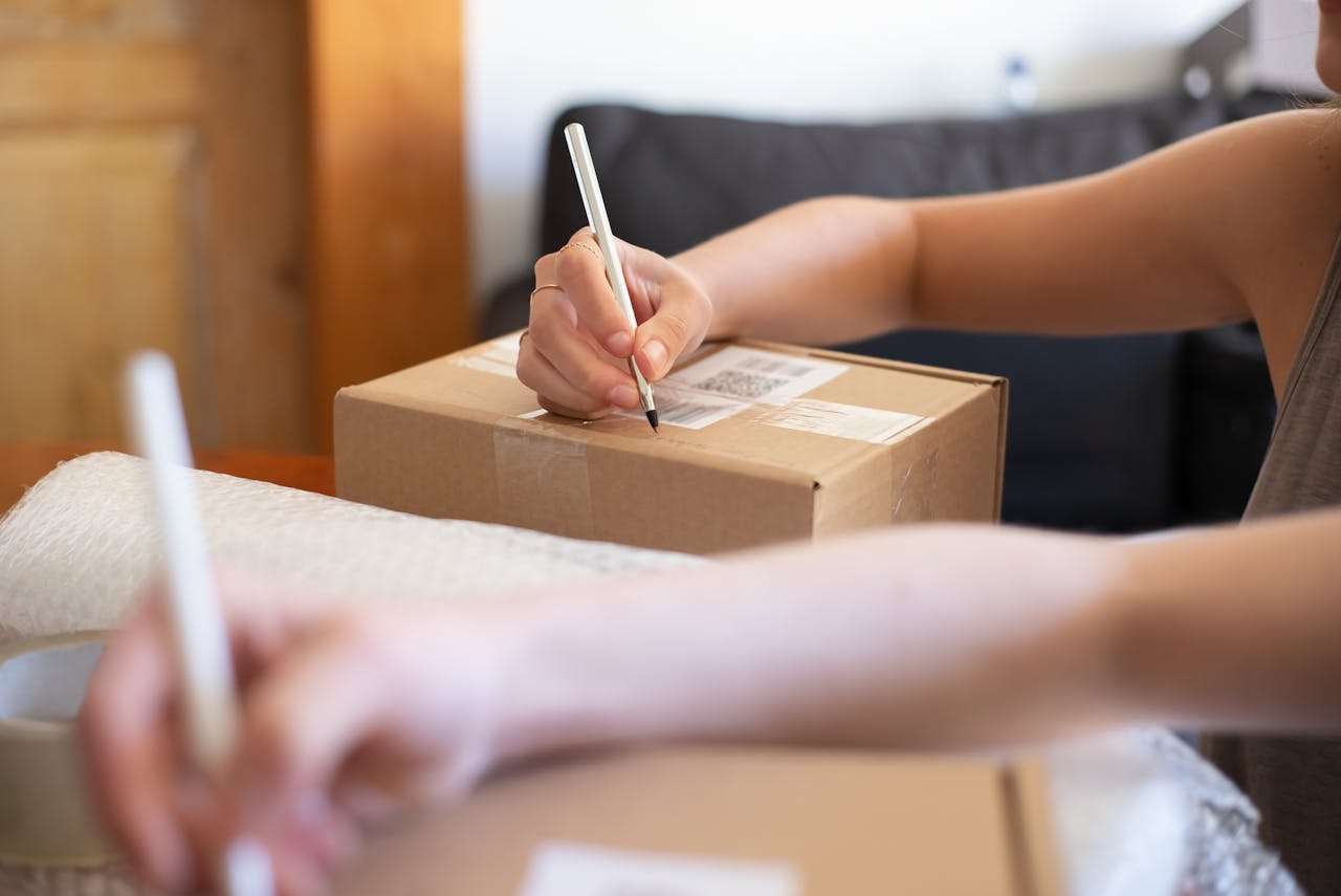 Person Writing on Brown Cardboard Box