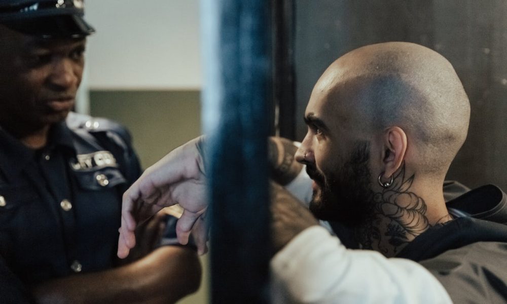 Bald Man with Tattoo in Jail Near a Policeman