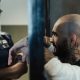 Bald Man with Tattoo in Jail Near a Policeman