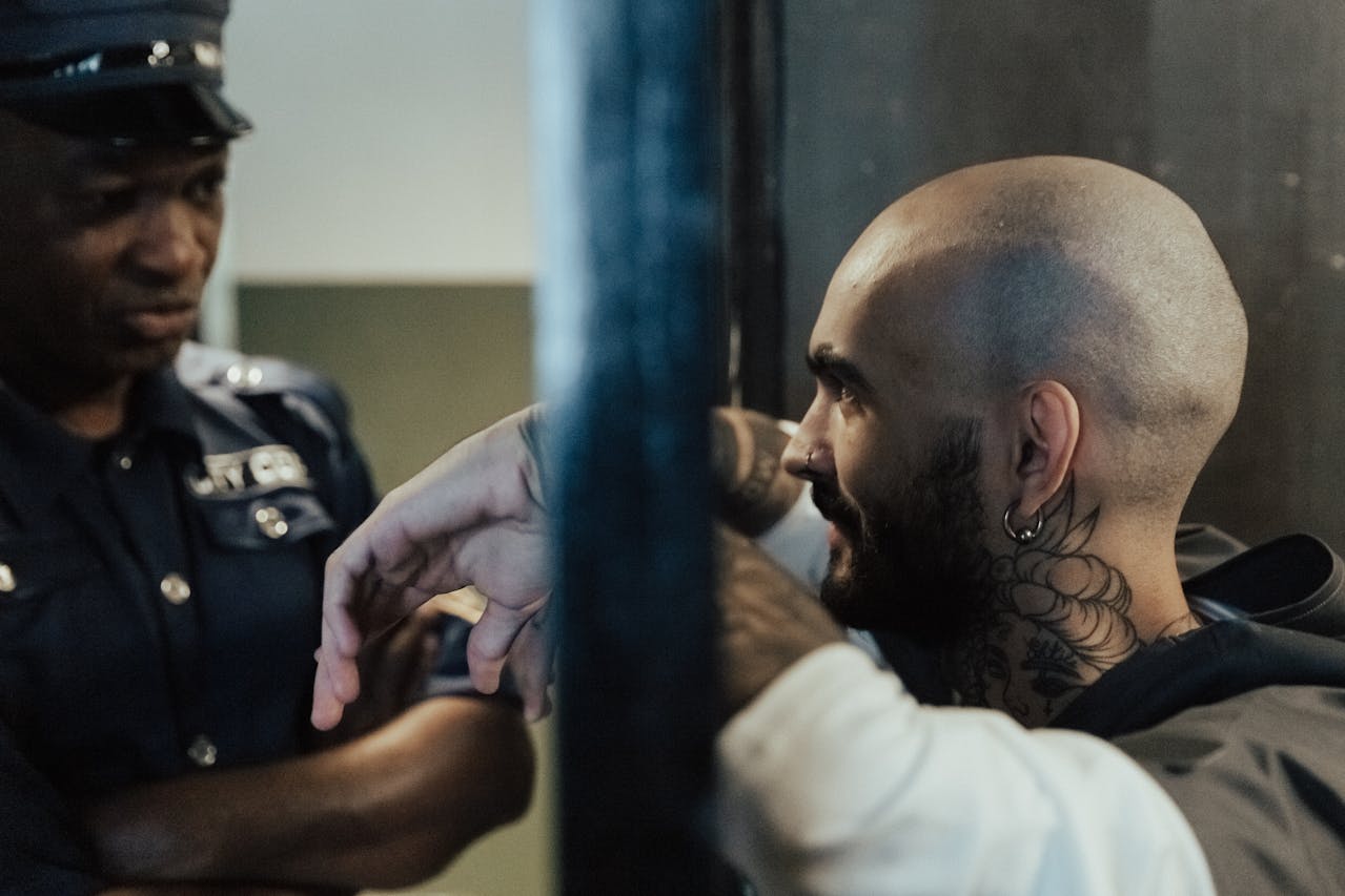 Bald Man with Tattoo in Jail Near a Policeman