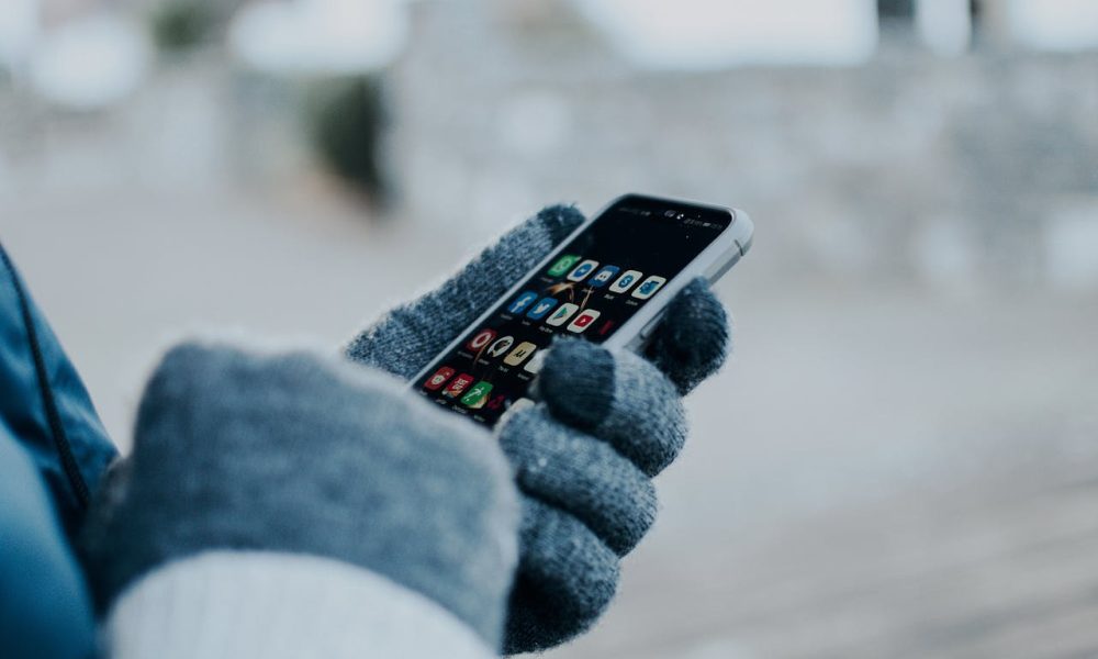 hand with gloves holding phone