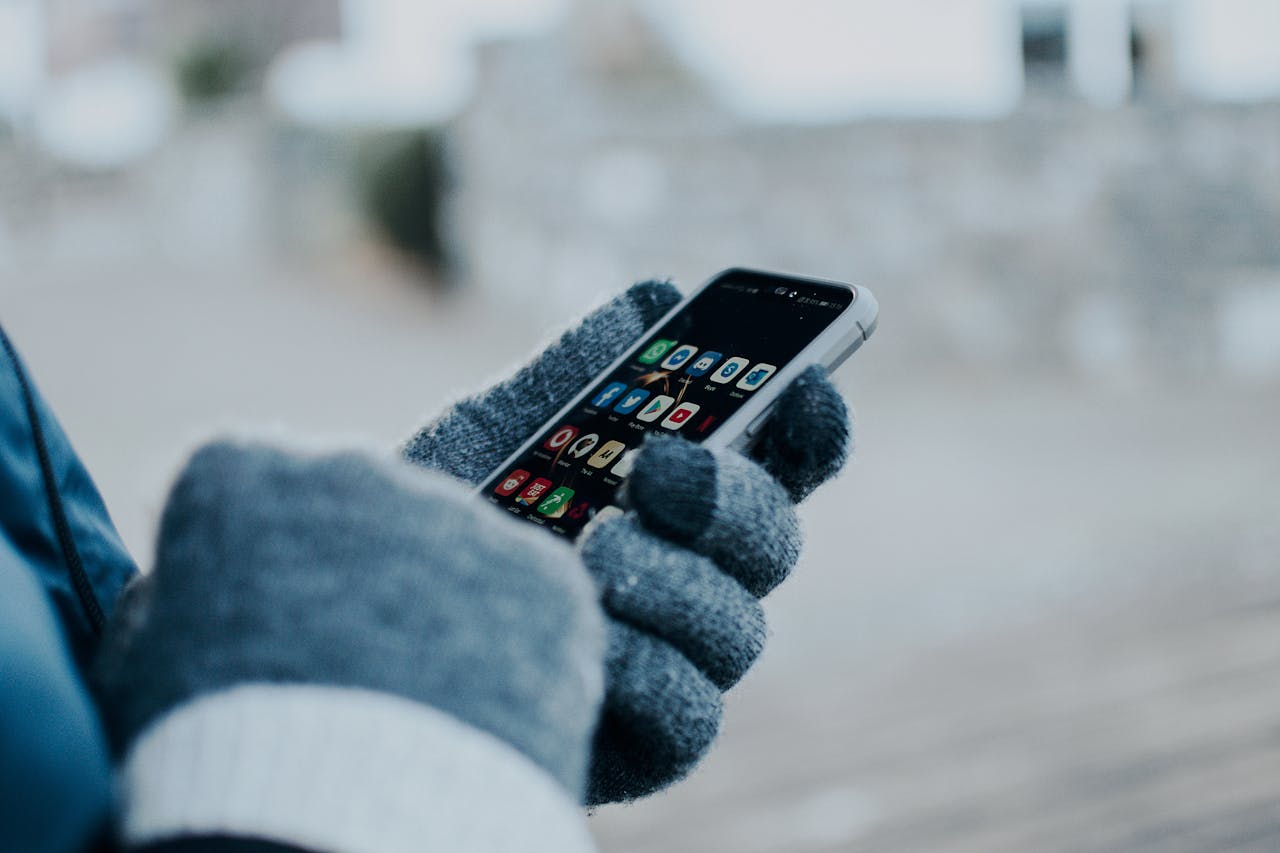 hand with gloves holding phone