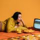 Woman in Yellow Long Sleeve Shirt Watching TV And Eating