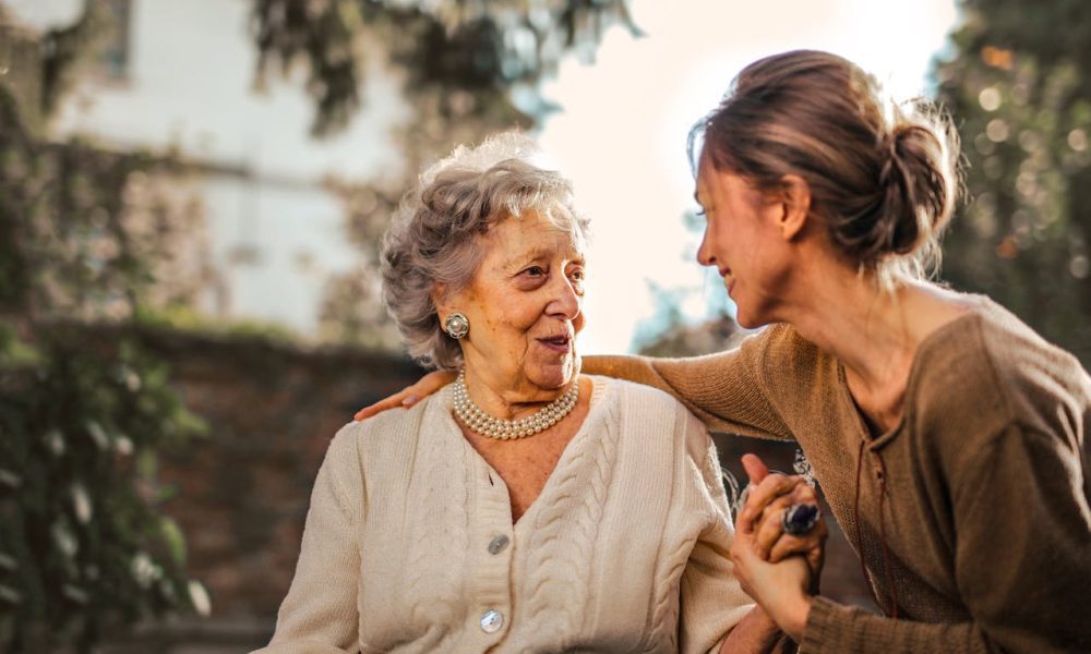 Joyful adult daughter greeting happy surprised senior mother in garden