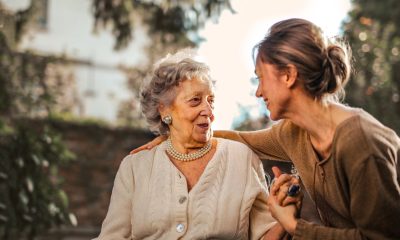 Joyful adult daughter greeting happy surprised senior mother in garden