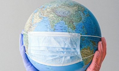 Hands With Latex Gloves Holding a Globe with a Face Mask