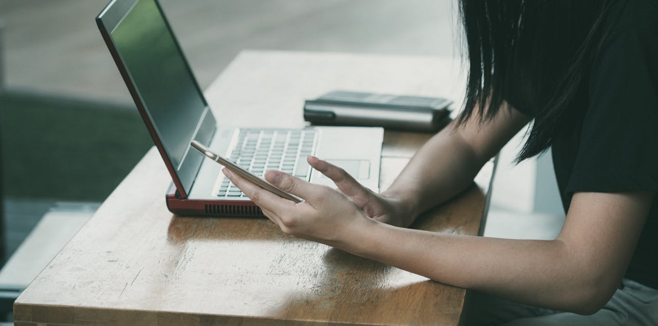 woman using phone and laptop